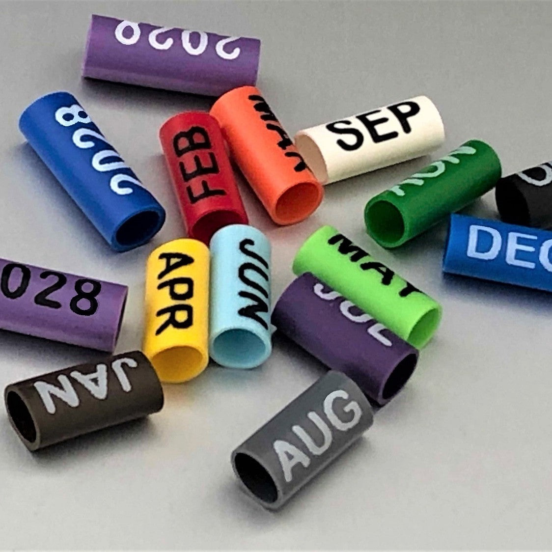 Colorful date markers with months and years printed on them arranged on a gray background by www.cablelabels.uk