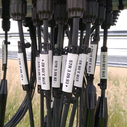 Set of black solar cables with white cable labels displaying solar pv numbers on a solar farm